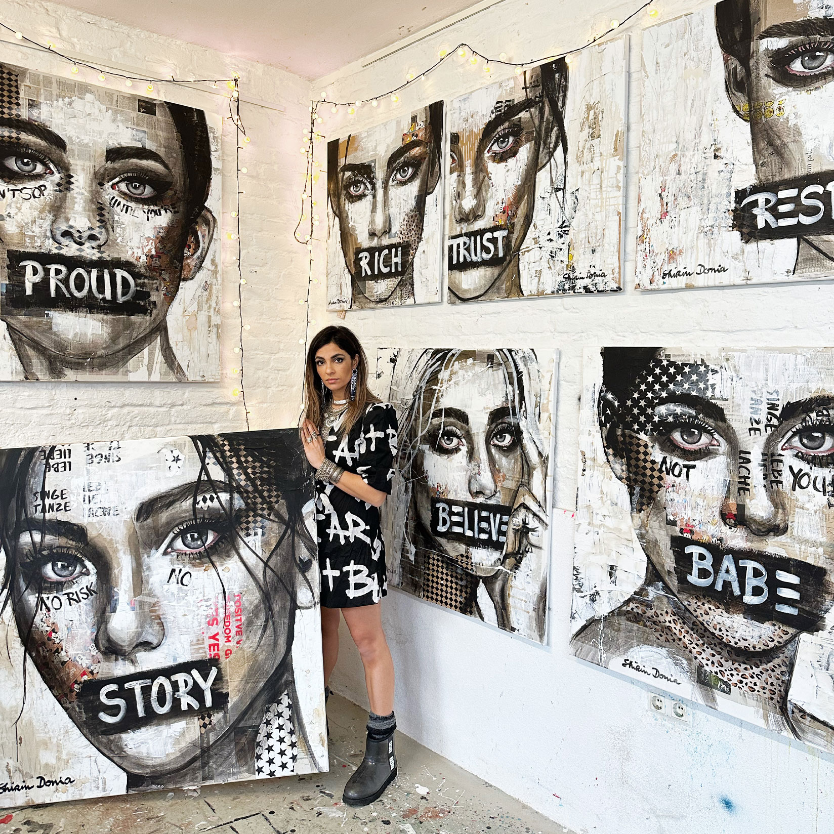 Shirin Donia in ihrem Atelier vor modernen Portraitgemälden mit großen Schriftzügen