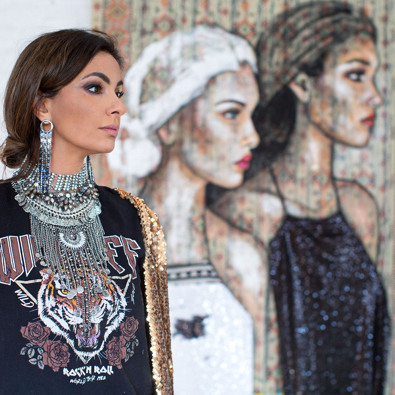 Künstlerin Shirin Donia vor einem modernen Gemälde mit zwei Frauenportraits